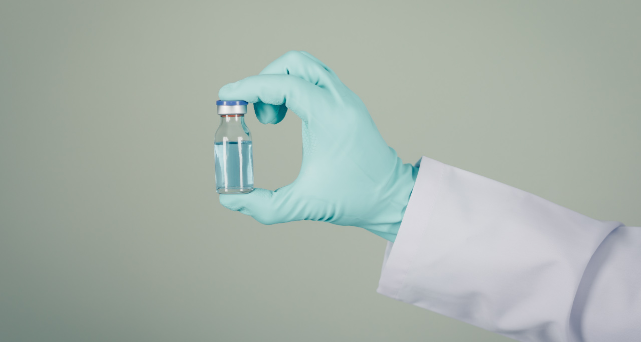 médico com luva verde segurando remédio em vidro transparente