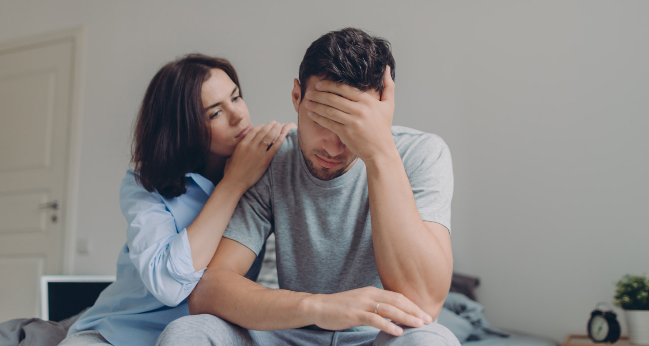homem preocupado, sendo acolhido por uma mulher.