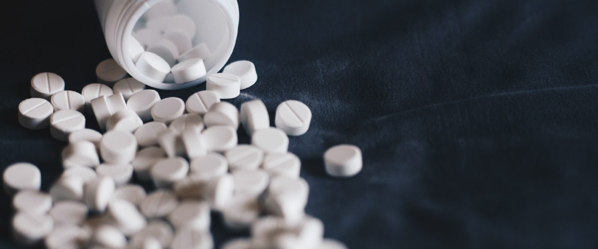 para-que-serve-sertralina Pote de medicamento com vários comprimidos caídos.